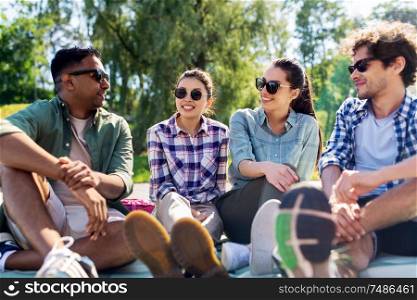 leisure, picnic and people concept - friends hanging out and talking outdoors in summer park. friends hanging out and talking outdoors in summer