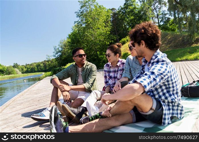 leisure, picnic and people concept - friends hanging out and talking outdoors in summer park. friends hanging out and talking outdoors in summer