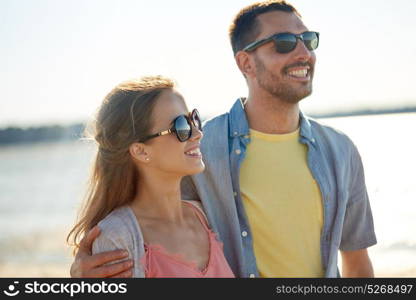 leisure, relationship and people concept - happy couple in sunglasses hugging on summer beach. happy couple in sunglasses hugging on summer beach