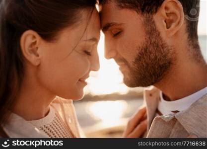 leisure, relationships and people concept - close up of happy couple with closed eyes on summer beach. happy couple with closed eyes on summer beach