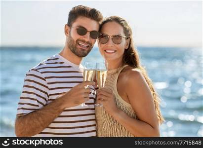 leisure, relationships and people concept - happy couple in sunglasses drinking ch&agne on summer beach. happy couple drinking ch&agne on summer beach