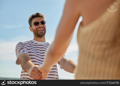 leisure, relationships and people concept - happy couple in sunglasses having fun on summer beach. happy couple having fun on summer beach