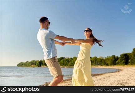 leisure, relationships and people concept - happy couple in sunglasses holding hands on summer beach. happy couple holding hands on summer beach