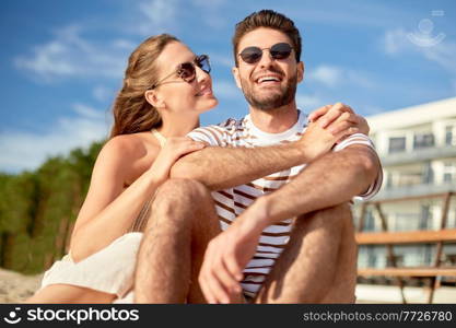 leisure, relationships and people concept - happy couple in sunglasses sitting on summer beach. happy couple sitting on summer beach