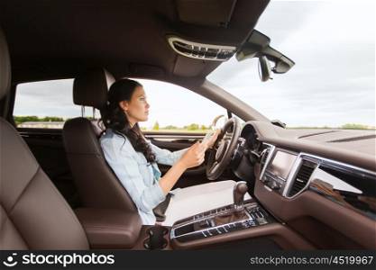 leisure, road trip, technology, travel and people concept - happy woman driving car with smarhphone
