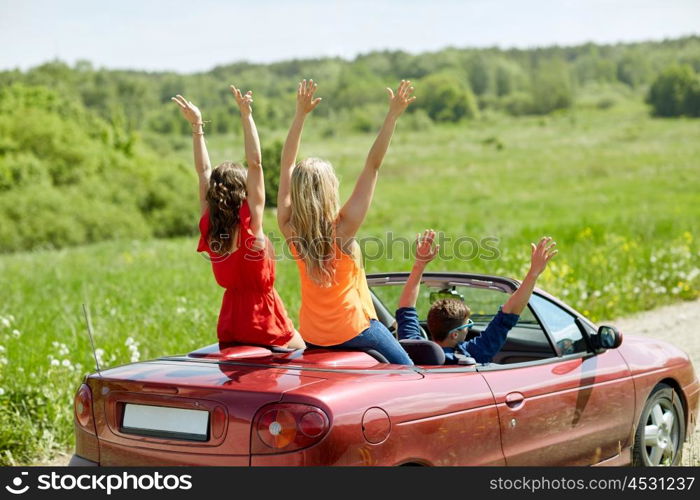 leisure, road trip, travel and people concept - happy friends driving in cabriolet car at country and waving hands