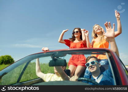 leisure, road trip, travel and people concept - happy friends driving in cabriolet car along country road