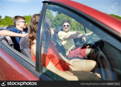 leisure, road trip, travel and people concept - happy friends driving in cabriolet car along country road and talking