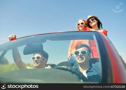 leisure, road trip, travel and people concept - happy friends driving in cabriolet car along country road