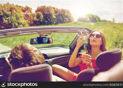 leisure, road trip, travel and people concept - happy friends driving in cabriolet car along country road and blowing bubbles. friends driving in car and blowing bubbles