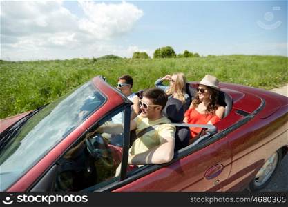 leisure, road trip, travel and people concept - happy friends driving in cabriolet car at country