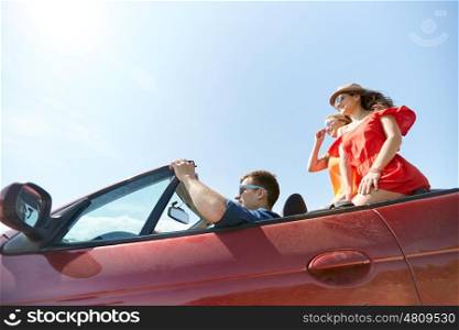 leisure, road trip, travel and people concept - happy friends driving in cabriolet car outdoors