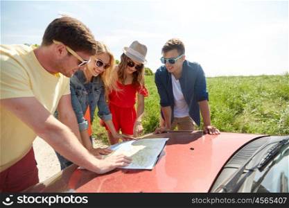 leisure, road trip, travel and people concept - happy friends with map and car searching location at country