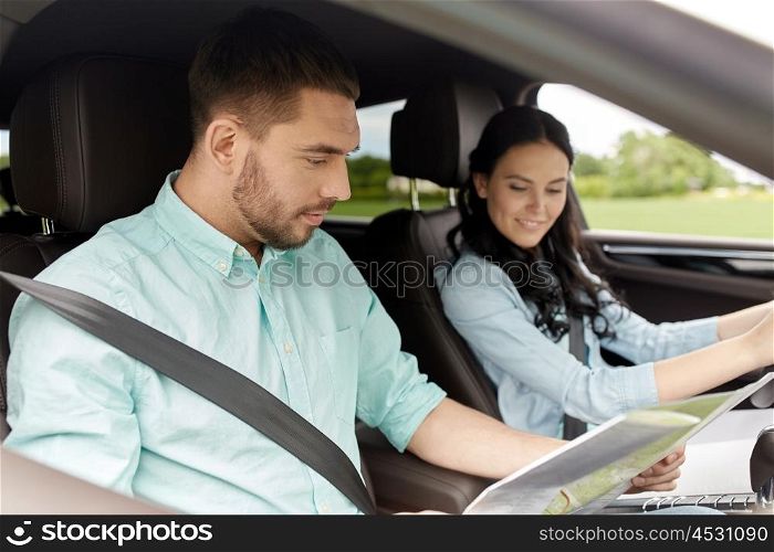 leisure, road trip, travel and people concept - happy man and woman driving in car and searching location on map