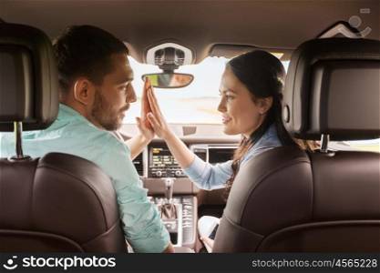 leisure, road trip, travel and people concept - happy man and woman making high five gesture and driving in car