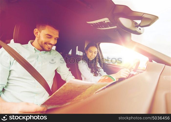 leisure, road trip, travel and people concept - happy man and woman driving in car and searching location on map. happy man and woman with road map driving in car