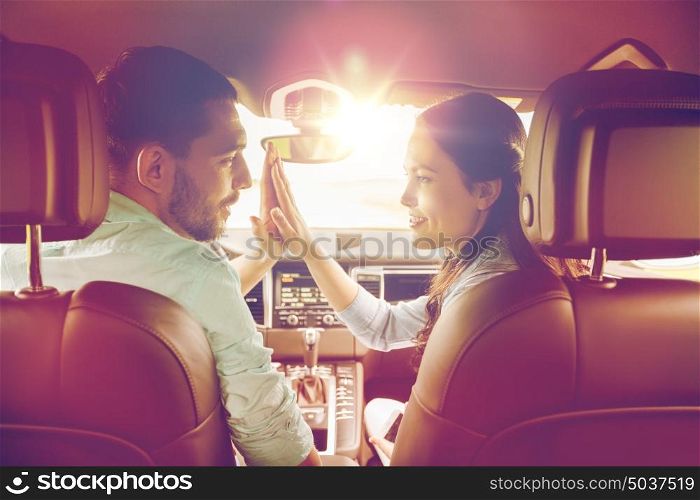 leisure, road trip, travel and people concept - happy man and woman making high five gesture and driving in car. happy man and woman driving in car