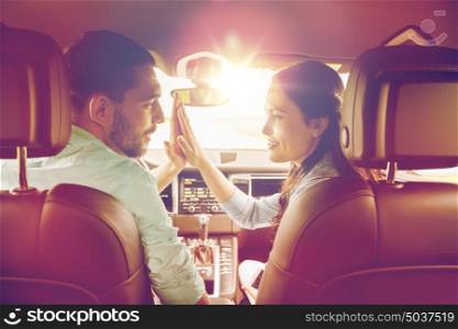 leisure, road trip, travel and people concept - happy man and woman making high five gesture and driving in car. happy man and woman driving in car