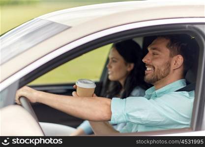 leisure, road trip, travel, family and people concept - happy man and woman driving in car with coffee