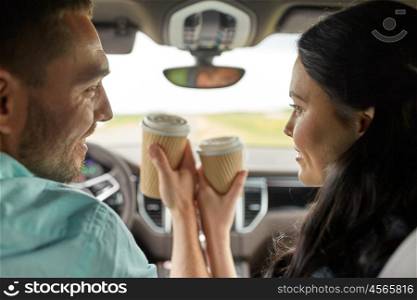 leisure, road trip, travel, family and people concept - happy man and woman driving in car with coffee