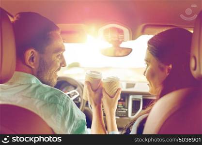 leisure, road trip, travel, family and people concept - happy man and woman driving in car with coffee. happy man and woman driving in car with coffee