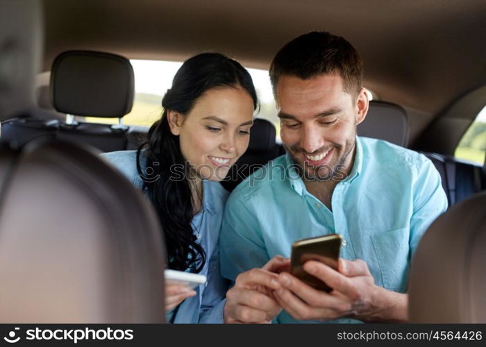 leisure, road trip, travel, technology and people concept - happy man and woman with smartphones driving in car