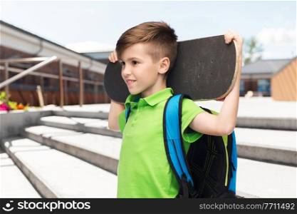 leisure, school and people concept - happy smiling student boy with backpack and skateboard over city street background. happy student boy with backpack and skateboard