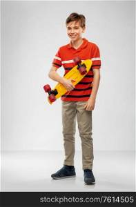 leisure, sport and people concept - happy smiling boy with short skateboard over grey background. smiling boy with short skateboard