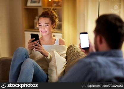 leisure, technology and internet addiction concept - couple with smartphones at home in evening. couple with smartphones at home in evening