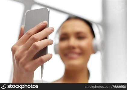 leisure, technology and people concept - close up of happy woman with smartphone and headphones. close up of woman with smartphone and headphones