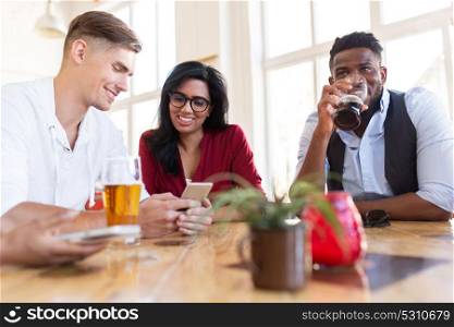 leisure, technology and people concept - group of happy international friends with smartphone drinking beer at bar. happy friends with smartphone drinking beer at bar