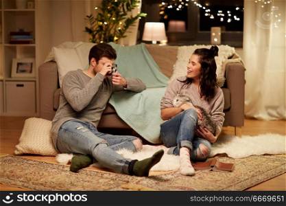 leisure, technology and people concept - happy couple with camera photographing at home. happy couple with camera photographing at home. happy couple with camera photographing at home