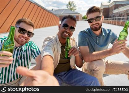 leisure, technology and people concept - happy male friends taking selfie and drinking beer on street in summer. men drinking beer and taking selfie on street