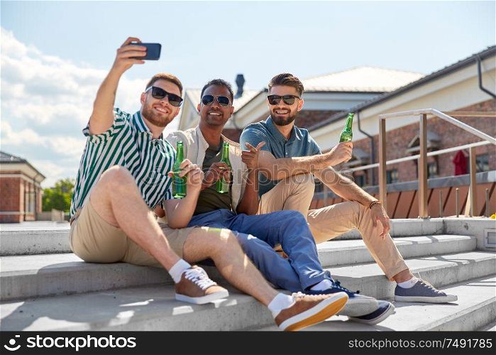 leisure, technology and people concept - happy male friends taking selfie by smartphone and drinking beer on street in summer. men drinking beer and taking selfie by smartphone