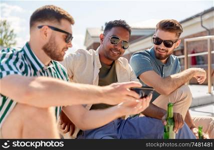 leisure, technology and people concept - happy male friends with smartphone drinking beer and talking on street in summer. men with smartphone drinking beer on street