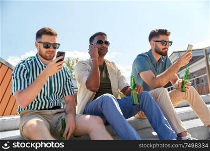 leisure, technology and people concept - happy male friends with smartphones drinking beer and talking on street in summer. men with smartphones drinking beer on street