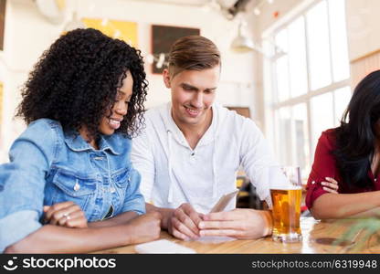 leisure, technology and people concept - happy man and woman with smartphone and beer at bar or restaurant. happy man and woman with smartphone at bar