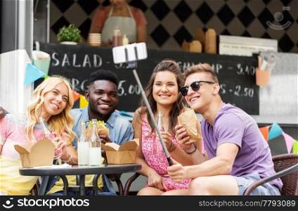 leisure, technology and people concept - happy young friends with food and non alcoholic drinks and taking selfie at food truck. happy young friends taking selfie at food truck
