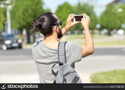 leisure, technology and people concept - hipster man taking picture or video by smartphone on street