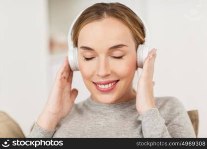leisure, technology and people concept - smiling woman with headphones listening to music at home. woman with headphones listening to music at home