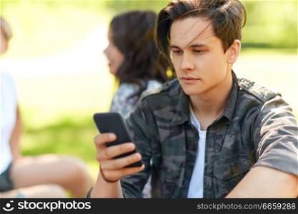 leisure, technology and people concept - woman using smartphone with friends at summer park. man using smartphone with friends at summer park