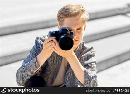 leisure, technology and people concept - young man or teenage boy with digital camera photographing in city. young man with camera photographing in city
