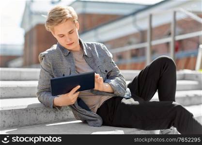 leisure, technology and people concept - young man or teenage boy with tablet pc in city. young manor teenage boy with tablet pc in city