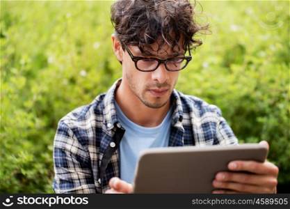 leisure, technology, communication and people concept - close up of creative man in glasses with tablet pc computer outdoors