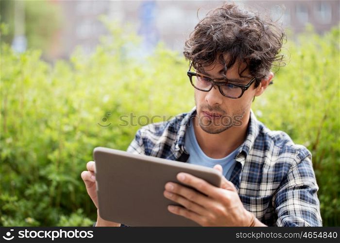 leisure, technology, communication and people concept - close up of creative man in glasses with tablet pc computer outdoors