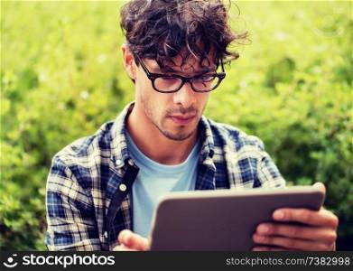 leisure, technology, communication and people concept - close up of creative man in glasses with tablet pc computer outdoors. man in glasses with tablet pc computer outdoors