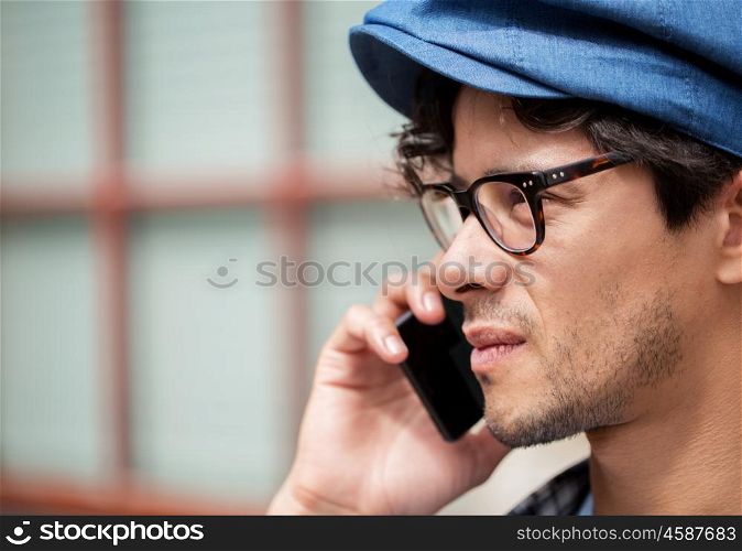 leisure, technology, communication and people concept - close up of man hipster in eyeglasses calling on smartphone on street