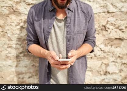 leisure, technology, communication and people concept - close up of man with smartphone at stone wall on street
