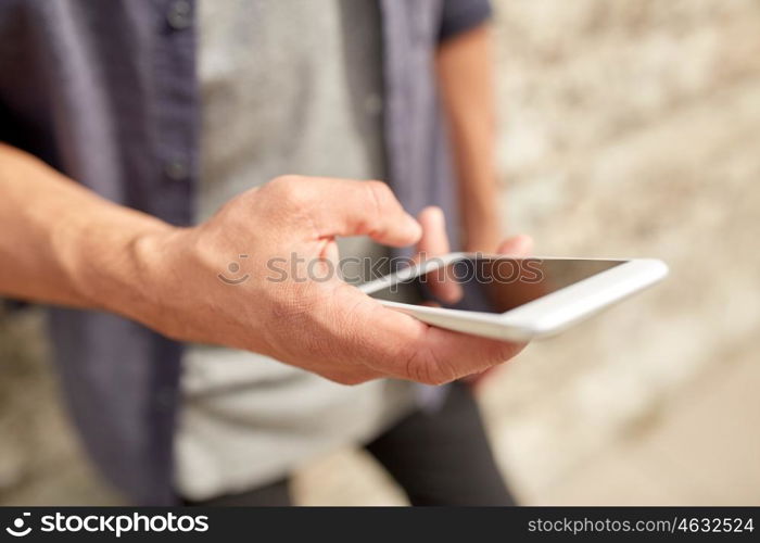 leisure, technology, communication and people concept - close up of man with smartphone at stone wall on street