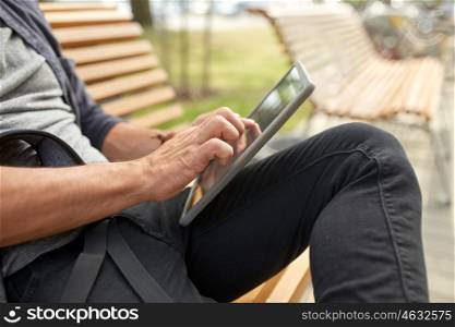 leisure, technology, communication and people concept - close up of man with tablet pc computer and bag sitting on city street bench